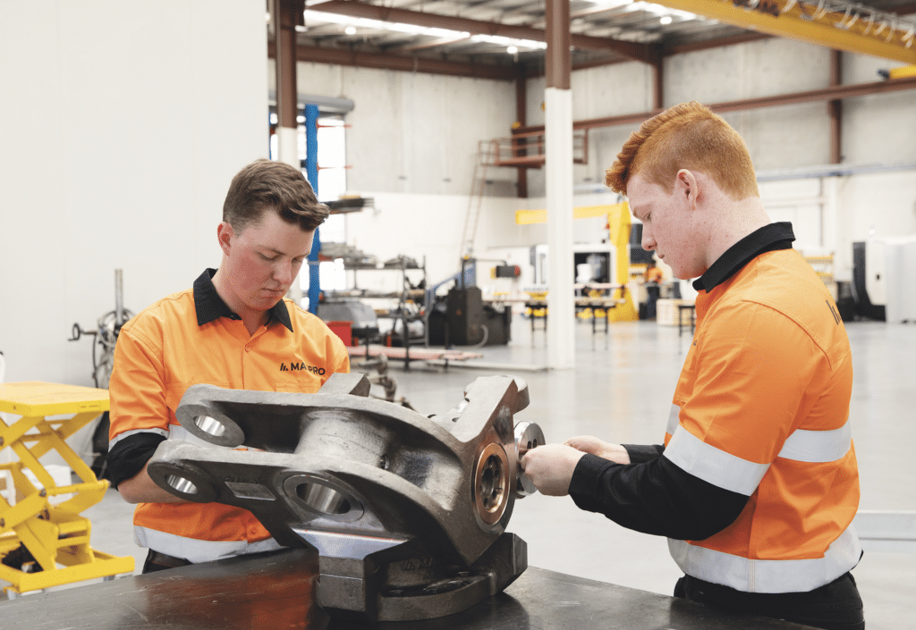 Two MASPRO technicians inspecting a large mining equipment component in a bright and modern workshop